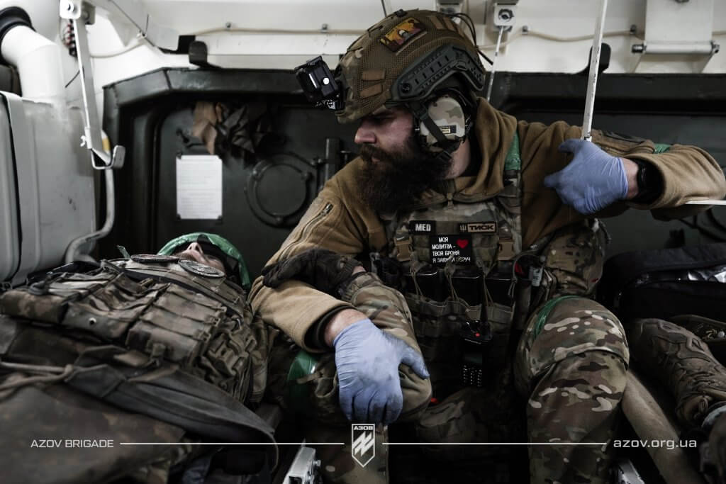 Медик «Азову» з пораненим бійцем під час евакуації з поля бою