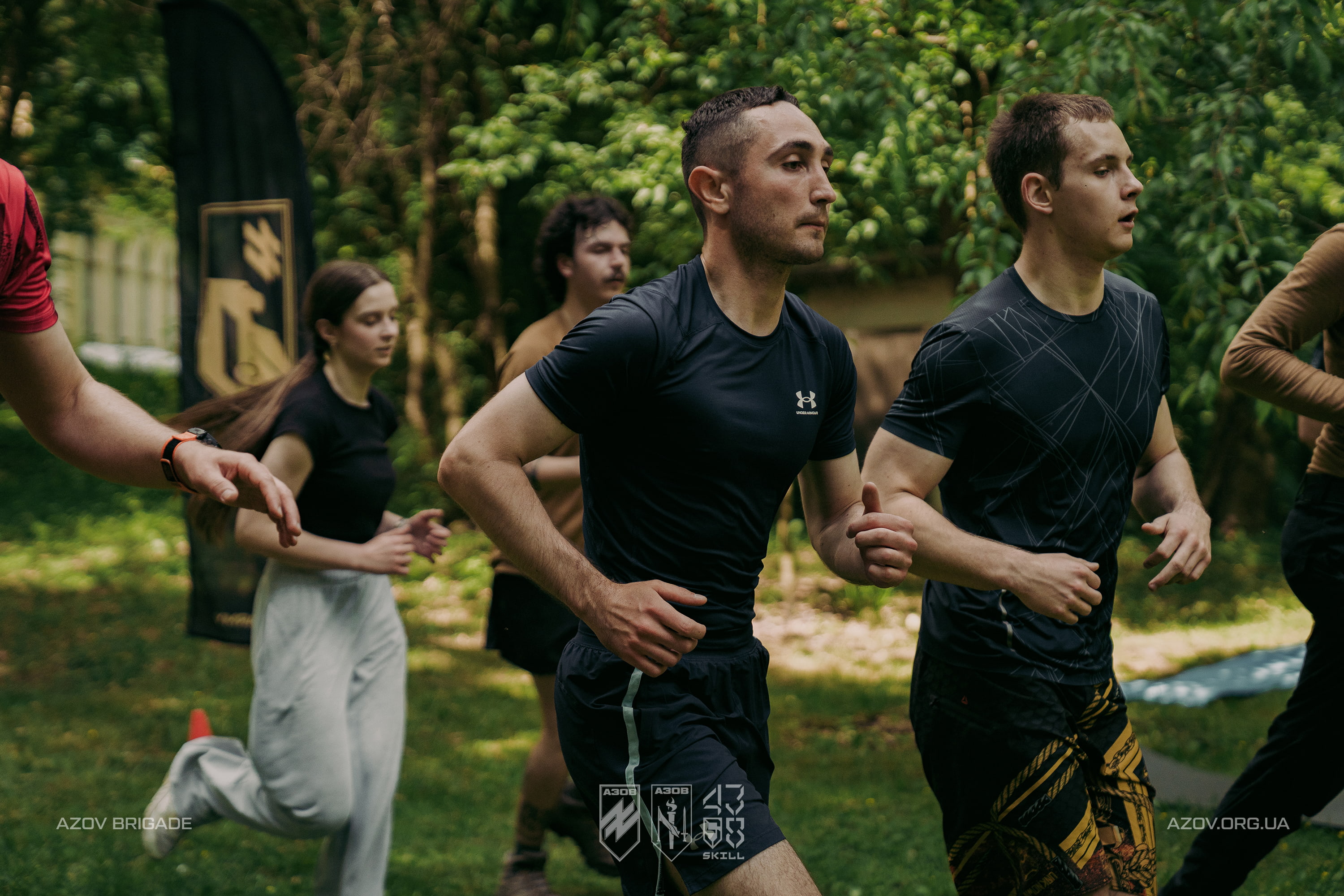 Учасники проєкту Azov Skill виконують бігову розминку під час тренування на відкритому повітрі.